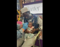 Dad hold baby while her ears gets pierced