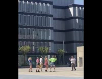 Group different color shirt dance outside building.