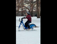 Boy rides citibike with skis at park