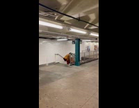 Person in orange jacket gets couch down stairs subway