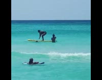 Girl falls off yellow paddle board ocean 