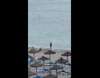 Collab IITW - Woman in black shirt dances at the beach at sundown nipa hut umbrellas