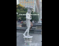 Human statue guy stands still white column 