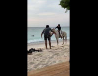 Woman rides horse for photo at beach