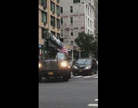 Rolling justice truck with lunch atop a skyscraper display in the trunk, men sit on metal beam with lunch