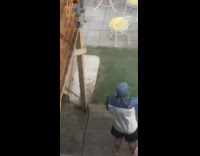 Man raincoat selfie video water hose backyard