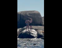 Man in briefs poses at beach rocks