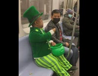small man dressed as leprechaun puts coin in bucket 
