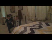 little boy in black jumps on yellow bed