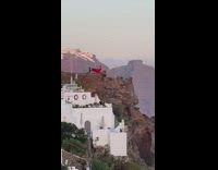 Woman red dress on cliff windy santorini
