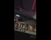 Woman in white jacket poses with her back at the parking lot