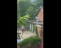 White hat person dances brick garage rooftop 
