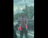 Guy in clown makeup juggling for cars stopped at traffic light