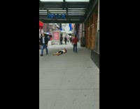 Shirtless guy sleeping on sidewalk on bag in front of an AMC theaters