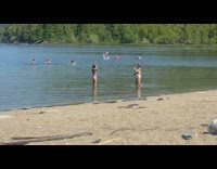 Woman in bikini poses with kids nearby at the beach