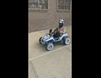 Brown jacket guy rides blue toy car 