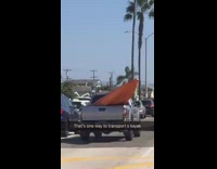 giant orange kayak in grey truck