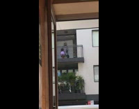 Man in checkered outfit dances at the balcony