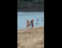 Two women in bikini wears a pumpkin head at the beach