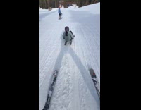 Man skiing with 2 people passing through underneath him