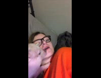 Girl orange shirt lets pet pig lick her face