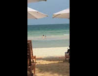 Little kid photographs girl sitting beach shore