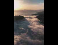 Brown boots guy sits rock above clouds 