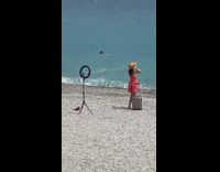 Woman in pink dress takes beach photo with luggage