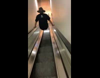 Man on both handrails of the down escalator with legs straight