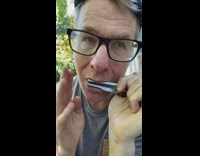 Man black frame glasses plays black jaw harp with mouth