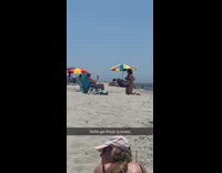 Girl kneels beach sand colorful striped umbrella 