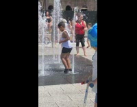 Boy stands directly on top of floor fountain jet, water shoots him in the butt