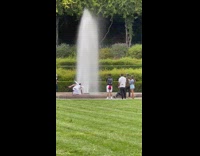 Guy in angel costume plays with water fountain 