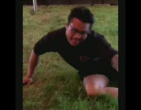 Drunk guy grabs boxed wine while laying on grass in front of live band stage and chugs wine