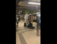 Guy in pink tropical shirt sings and plays marimba drums at subway station