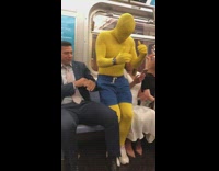 Guy in yellow morphsuit bodysuit runs around on subway train, shoves and sits between couple
