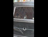 Black hearse parked on street with funny stickers 