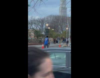 Man dances on street balancing trash can with basketballs