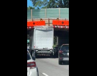 Tall truck stuck under bridge at parkway