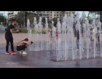 Girl poses by water fountain kids run 