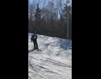 Guy rides skis and jumps over red net, then falls down into snow