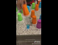 Friends try to find shot glass underneath solo cups 