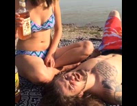 Girl pours rum into boyfriends mouth by the beach 