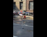Guy sits in beach chair under umbrella on sidewalk 