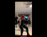 Guy in orange hat dances by himself in the living room, slaps thigh