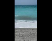 Lady standing in ocean holds phone up