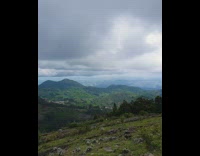 Guy standing on top of hill looks at view 