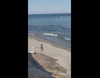 Woman in cyan sports bra exercises at the beach