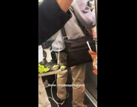 Guy holds Chucky doll with orange hair and green headband on subway train