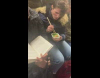 Woman eats green vegetables with chopsticks while man reads book on subway train